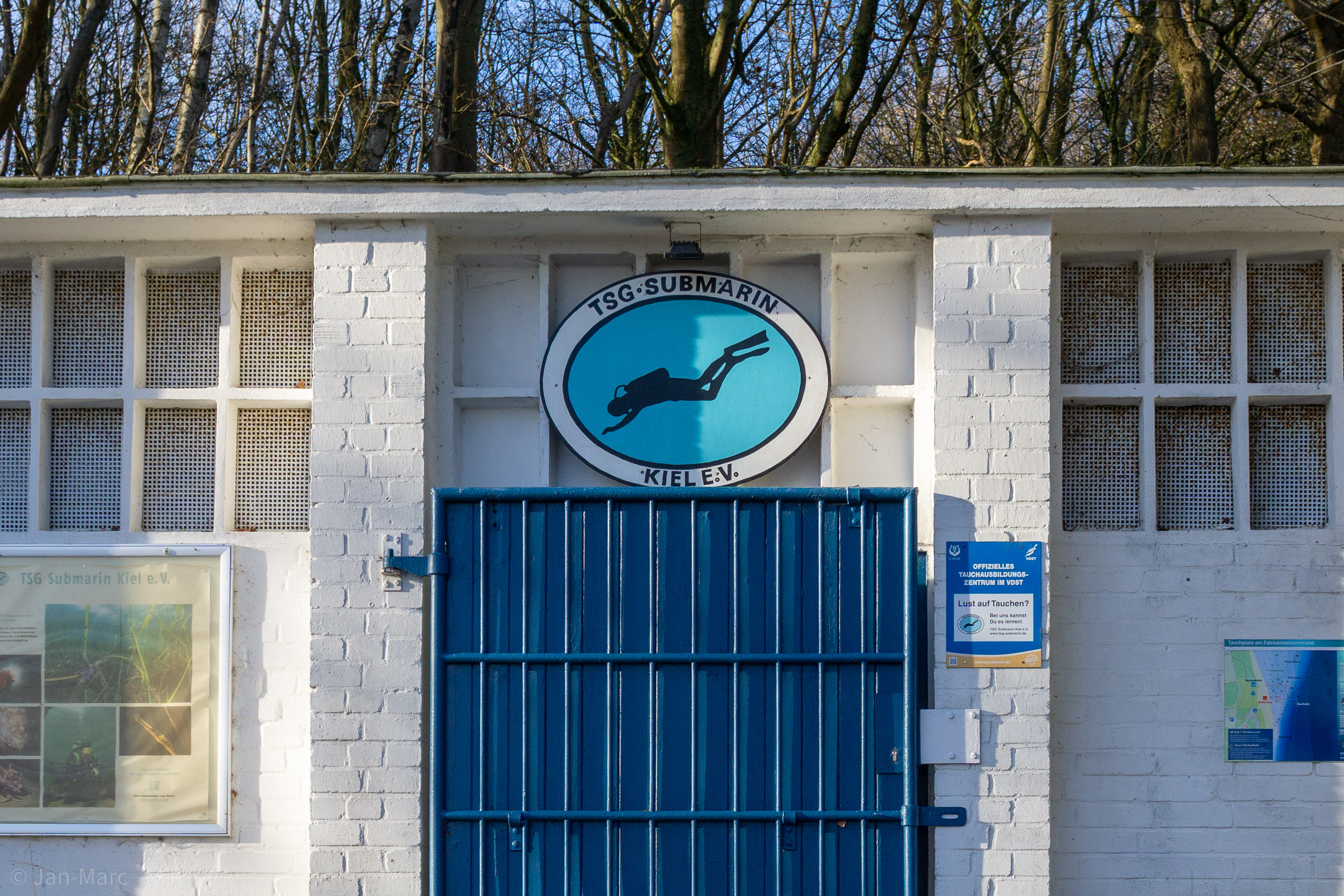 Vereinshaus am Falkensteiner Strand im Winter mit blauem Tor und Vereinslogo